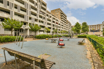 an empty playground area in the middle of a large apartment building with several children playing...