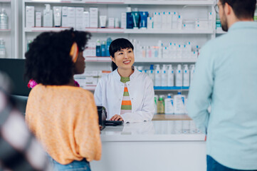Japanese woman pharmacist selling drugs to a customer in a pharmacy