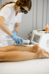 Young worker of a beauty salon during hair removal procedure on a woman's legs. Depilation concept and beauty procedures