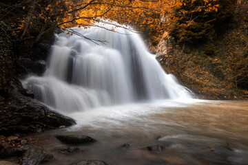 Autumn landscape with waterfall and rocks in the forest, long exposure