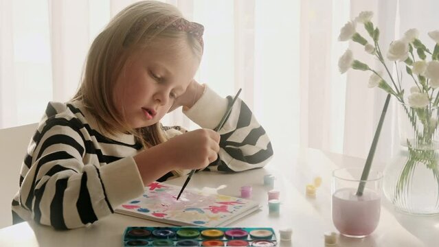 Little kid girl artist drawing coloring picture with paints and brushes. Child hobby creative art activity at home play alone. 