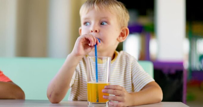 Cute children drinking soda or soft drink with straw in a fast food restaurant