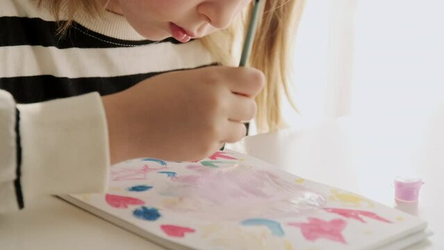 Little kid girl artist drawing coloring picture with paints and brushes. Child hobby creative art activity at home play alone. 