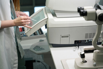 Ophthalmologist in a medical gown works on modern equipment