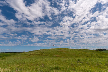 The American flag on the hill with white clouds and blue skies at Fort Juelson historical site just outside of Underwood, Minnesota United States.
