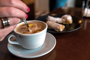 Kobieta miesza kawę w filiżance, obok filiżanki talerzyk ze słodkimi ciastkami © Kamil_k2p