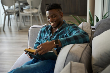 Happy African American guy sitting on the sofa