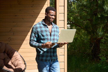 African American man walked out onto wooden terrace with laptop
