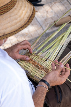 Close-up view of a man's hands weaving a canary wicker basket