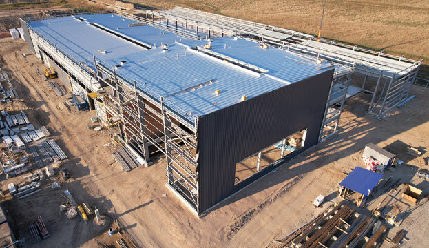 Warehouse Construction from metal structure. Industrial building on light gauge steel framing. Frame of modern hangar or factory. Construction site with steel structure warehouse. Top view on a roof.