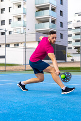 Young adult man playing Pickleball. Portrait of a man performing a backhand shot in a pickleball match