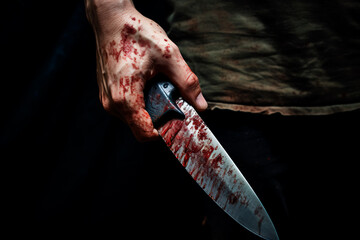 Scary conceptual image of bloody knife in hand.