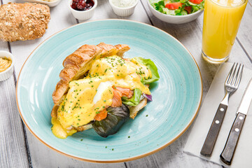 Eggs Benedict Breakfast Plate with Salmon and Croissant, Gourmet Lunch: Tasty Fried Eggs and Toasted Croissant, Healthy Brunch Salad with Fresh Vegetables