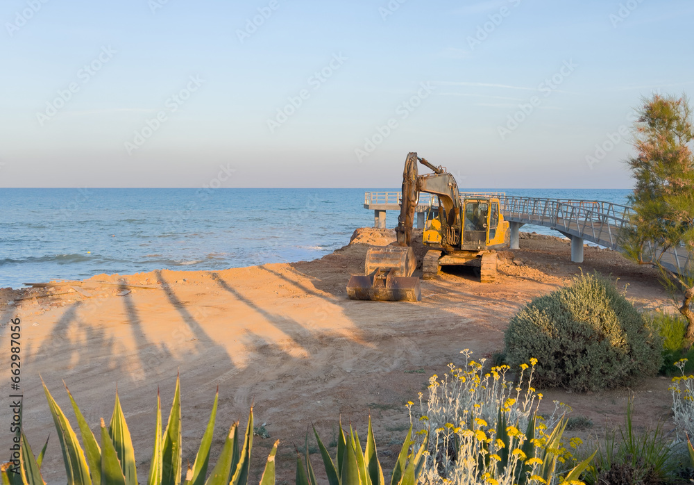 Canvas Prints beach renovation. excavator on pier construction near sea beach. excavator laying stones and rubble 