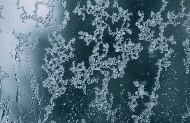 Frozen window glass with melting ice. Wet window background.
