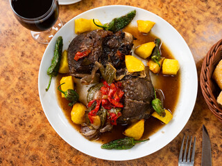 Main dish is pork chop garnished with baked sweet red and green peppers,onions,potatoes.Meat is served with olives, white bread and dry wine