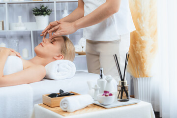 Obraz na płótnie Canvas Caucasian woman enjoying relaxing anti-stress head massage and pampering facial beauty skin recreation leisure in dayspa modern light ambient at luxury resort or hotel spa salon. Quiescent