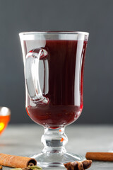 Close-up of glass with hot mulled wine and ingredients on dark background. Christmas drink concept