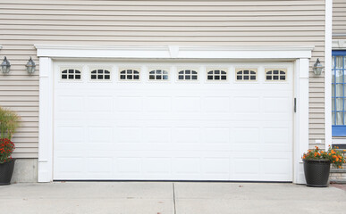 garage door of a cozy house, symbolizing security and home comfort, framed by a neatly landscaped front yard on a sunny day