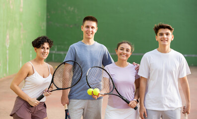 Group photo of positive young men and women standing on frontenis court after another game