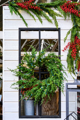 Fototapeta na wymiar Christmas decoration, evergreen wreath in a window of a fake white wall 
