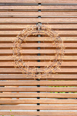 Wire and twinkle light wreath hanging on a modern wood wall

