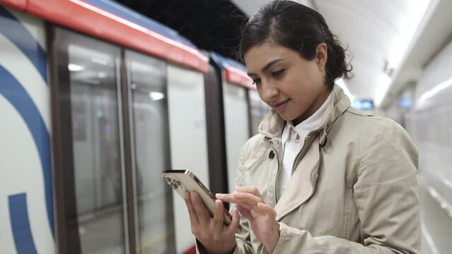 Happy woman in subway. Girl using smartphone internet surfing communication online. Scrolling pictures in application, typing message. Female student holding phone checking news. Public transport. 4K