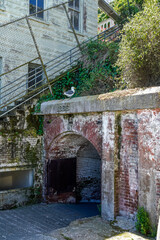 Exterior of two buildings and a walkway at Alcatraz Island. Former federal penitentiary in San Francisco, California. Sea gull sitting above the red bricks.