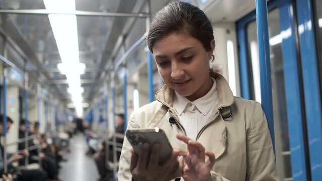 Portrait of young woman in subway. Happy girl using smartphone internet surfing communication online. Female student scrolling pictures in application, typing message. Browsing social network 4K