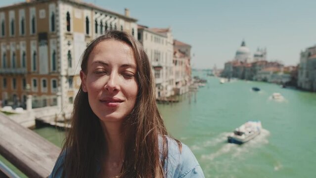 Close-up of beautiful young woman looking at camera on Venice canal background