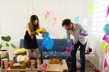 Young woman and man cleaning the mess after celebrating a party