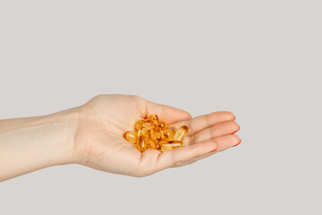 Closeup of woman hand handful of pills capsules, nutritional supplement, vitamins, medicine. Indoor studio shot isolated on gray background.