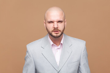 Portrait of aggressive bald bearded man looks grumpy, feels offended and displease, clenched teeth,...