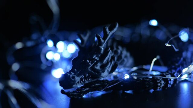 Black dragon and blue lights of garlands on a black background.Year of the dragon background. 4k footage