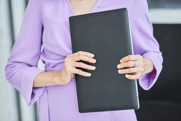 A girl is holding a laptop in her hands - an excellent device for a businesswoman. Technology not...