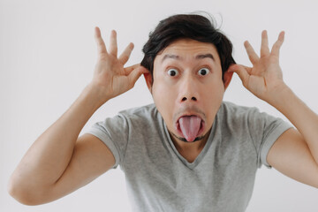 Asian man make funny teasing face for humor isolated on white.