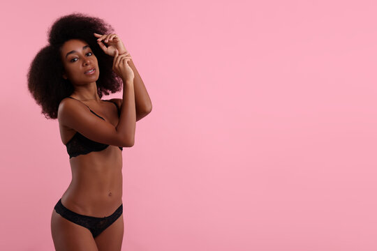 Beautiful woman in elegant black underwear on pink background, space for text