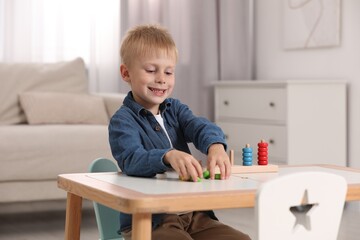 Cute little boy playing with stacking and counting game at table indoors. Child's toy