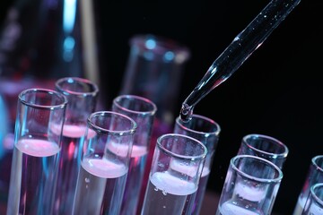 Dripping reagent into test tube on black background, closeup. Laboratory analysis