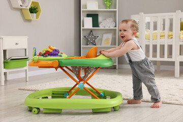 Cute baby making first steps with toy walker at home