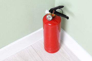 Red fire extinguisher near light green wall