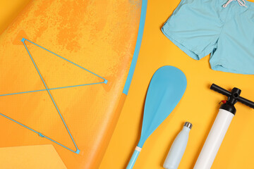 Flat lay composition with SUP board on orange background. Water sport