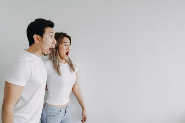 Naklejka premium Surprised and shocked face of exciting asian couple lover looking at empty space
