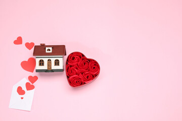 Long-distance relationship concept. House model, rose flowers and paper hearts flying out of...