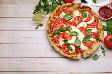 Delicious Caprese pizza with tomatoes, mozzarella and basil served on light wooden table, flat lay. Space for text