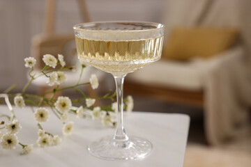 Glass of alcohol drink and flowers on table in room. Relax at home