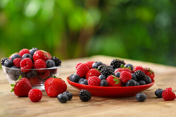Different fresh ripe berries on wooden table outdoors