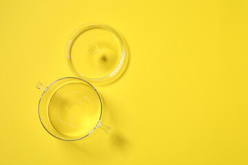 Empty glass pot and lid on yellow background, flat lay. Space for text