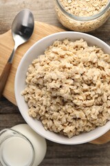 Tasty boiled oatmeal served on wooden table, flat lay