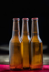 Cold beer bottles on wooden table with selective focu